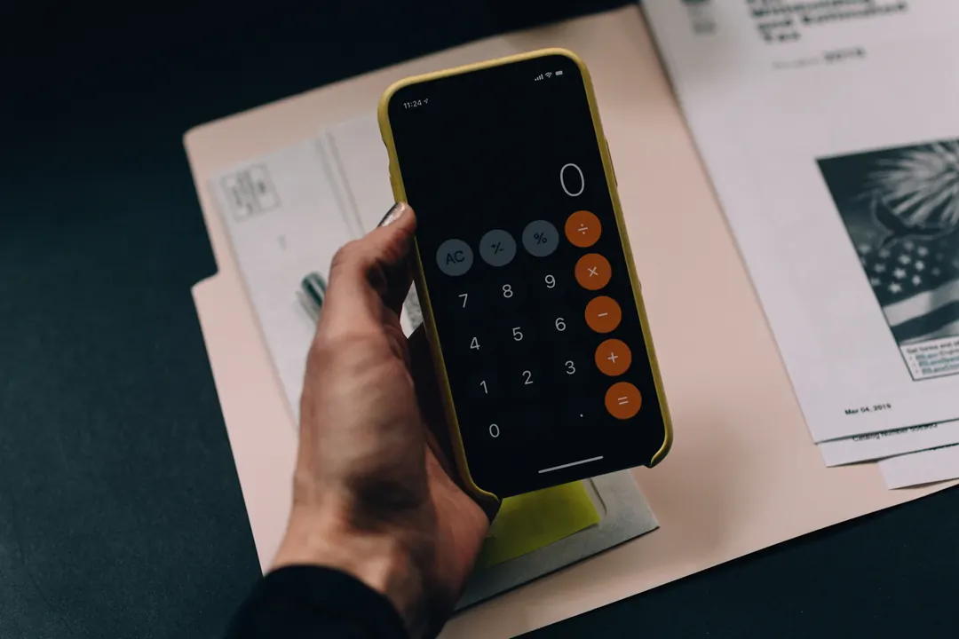 Hand holding a calculator over financial documents
