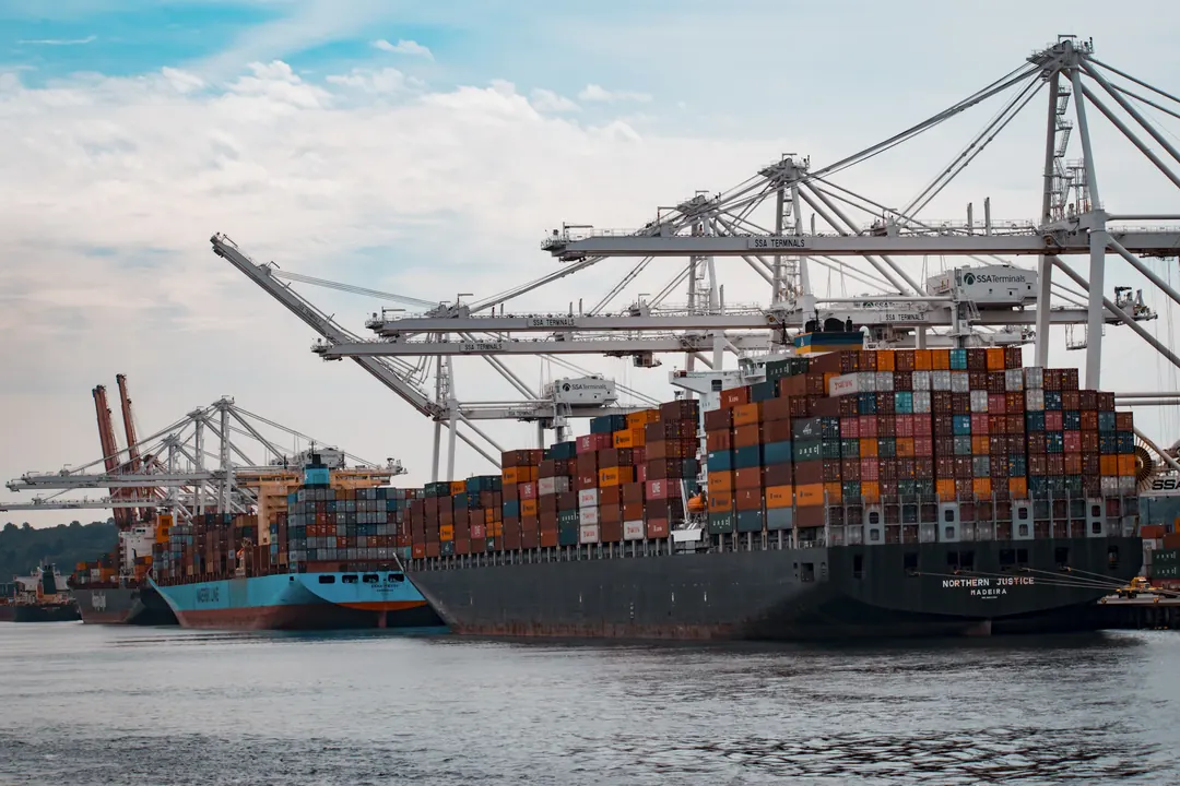 Container ship loaded with containers beside quay cranes